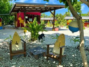 a cat standing next to two chairs and a table at Rangiroa Cottage in Avatoru
