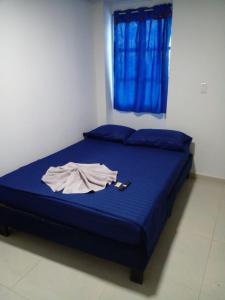 uma cama com lençóis azuis e uma camisa em Vivienda Turística el Refugio em Villavicencio