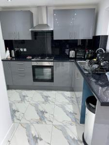 cocina con suelo de mármol y electrodomésticos de acero inoxidable en Home away from home en Leicester
