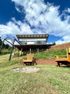 due sedie e una casa in cima a una collina di Chalé Rede - Entre Chalés - Pet Friendly a São Bento do Sapucaí