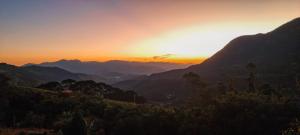 un tramonto su una valle con montagne sullo sfondo di Cabana do Camelo a São Bento do Sapucaí