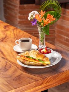 una mesa con un sándwich y una taza de café y flores en Naif Boutique Hotel, en Antigua Guatemala