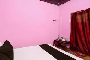 a bedroom with pink walls and a bed and a table at SPOT ON Mahadev Hotel in Prayagraj