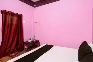 a bedroom with pink walls and a bed with a table at SPOT ON Mahadev Hotel in Prayagraj