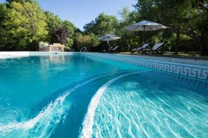 a blue swimming pool with an umbrella and chairs at Las Nubes Apart in Merlo
