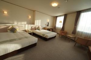 a hotel room with two beds and a desk at Hotel Areaone Hiroshima Wing in Higashihiroshima