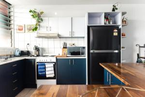 uma cozinha com armários azuis e um frigorífico preto em Breezy Treetop Escape in Stuart Park em Stuart Park