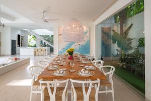 ein Esszimmer mit einem langen Tisch und weißen Stühlen in der Unterkunft Villa Luja in Canggu