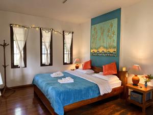 a bedroom with a large bed with blue sheets and orange pillows at Pairadise Hotel in Pai