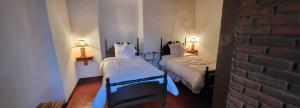 two beds in a room with two lamps on the wall at Alojamiento El Fresno in Mineral del Chico