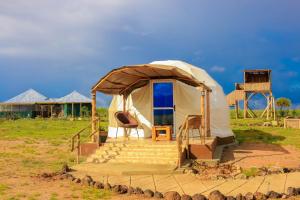 a yurt with a staircase and chairs in a field at Amanya 1-Bed Leopard Family with Mt Kilimanjaro vi in Amboseli