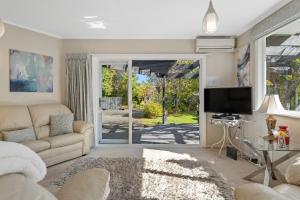 uma sala de estar com um sofá e uma televisão em Tui Paradise - Havelock North em Havelock North