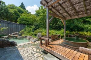 a hot tub on a wooden deck with a pergola at Gyokusui -Adult Only- in Higashiizu