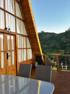 un tavolo in vetro e sedie su una terrazza in legno di Refúgio Suiço em Vargem Alta a Vargem Alta