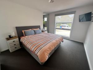 ein Schlafzimmer mit einem großen Bett und einem Fenster in der Unterkunft Fifteen Mercury in Venus Bay