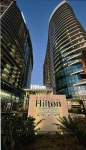 two tall buildings with a hilton sign in front of them at شقة فندقية في فندق هيلتون المعادي علي الكورنيش مباشرة in Cairo