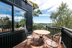 patio con mesa y sillas en el balcón en The Winemaker's Cottage - Coast & Country, en Omiha