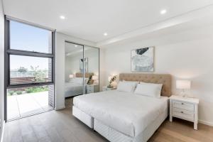 カイアマにあるPristine 3-Bed Kiama Unit with Courtyardのベッドと窓のある白い寝室