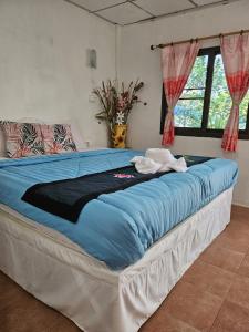 a large bed with a blue comforter in a bedroom at Thai Garden​ Resort​ Kanchanaburi​ in Kanchanaburi