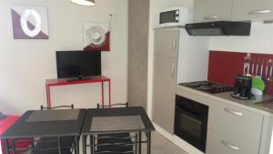 a small kitchen with a table and a refrigerator at Gîtes Macarien in Saint-Macaire