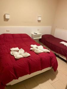 a bedroom with two beds with red sheets and towels at El viejo bar hotel in Perito Moreno