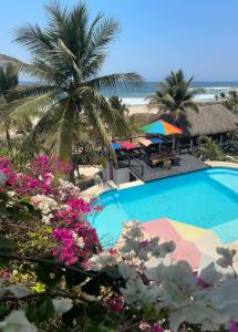 een zwembad met een palmboom en een strand bij Beachfront Paradise Boutique Hotel in Santa María Tonameca