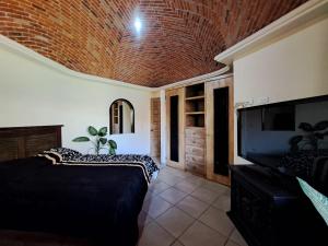 een slaapkamer met 2 bedden, een tv en een bakstenen plafond bij Rancho Labradores in Atotonilco