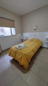 sypialnia z dużym łóżkiem i żółtym kocem w obiekcie El viejo bar hotel w mieście Perito Moreno