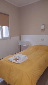 ein gelbes Bett mit zwei weißen Handtüchern drauf in der Unterkunft El viejo bar hotel in Perito Moreno