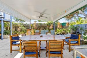 a patio with a wooden table and chairs at "Xanadu" Charming 2-Bed Retreat by Marcoola Beach in Bli Bli