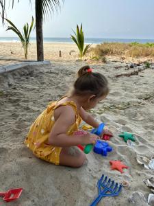 a little girl playing in the sand on the beach at Beachfront Paradise Boutique Hotel in Santa María Tonameca