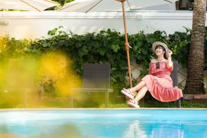 uma mulher de vestido vermelho sentada num baloiço junto a uma piscina em Touch Sea Boutique Hotel&Bistro em Ka Rorn