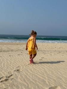 a little girl standing on the beach with footprints in the sand at Beachfront Paradise Boutique Hotel in Santa María Tonameca