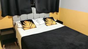 um quarto com uma cama com almofadas amarelas e brancas em Pousada uberaba em Uberaba