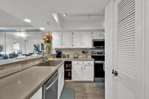 kuchnia z białymi szafkami, zlewem i urządzeniami w obiekcie Seagull Beachfront Condominiums w mieście South Padre Island