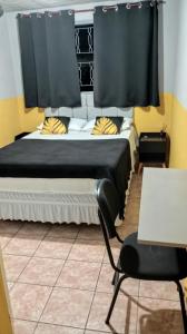 a bedroom with a bed and a chair and a table at Pousada uberaba in Uberaba