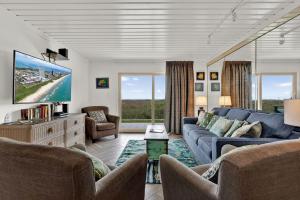 sala de estar con sofá azul y TV en Seagull Beachfront Condominiums en South Padre Island