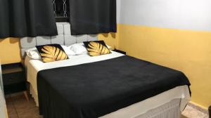 a bedroom with a bed with yellow and white pillows at Pousada uberaba in Uberaba