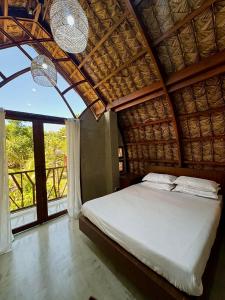 a bedroom with a bed and a large window at Your Brothers House Tribal Village in Legazpi