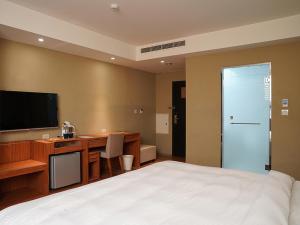 a bedroom with a bed and a desk and a television at River inn Zili in Kaohsiung
