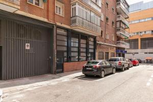 two cars parked on a street next to a building at Nice new duplex in front of Palacio VistaAlegre in Madrid