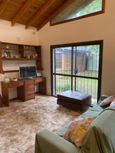 a living room with a bed and a desk and a window at Casa Vivienda Familiar Ituzaingo Centro Parque in Ituzaingó