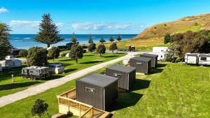 a row of portable toilets in a field with the ocean at Tatapouri Bay in Gisborne