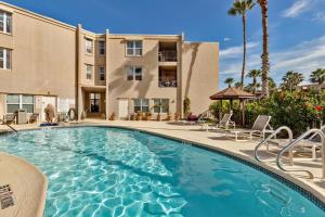 a swimming pool with chairs and a building at Beachside Bungalow: Surfside I #104 in South Padre Island