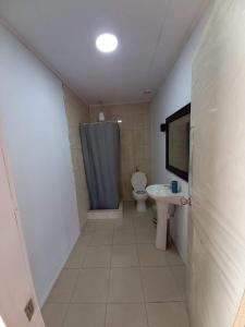 a bathroom with a toilet and a sink and a shower at Cabañas con tinajas coronel in Coronel