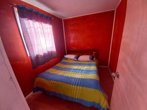 a small bedroom with a bed in a red room at Cabañas con tinajas coronel in Coronel