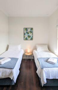 two beds in a room with a table with a candle at Charming Large Home: Modern Comfort and Convenience in Carey Park