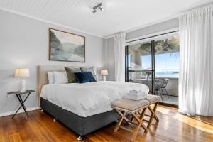 a bedroom with a large bed and a large window at Stargazers Waterfront Hot tub Cottage Tasmania in Clarence Point