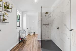 a white bathroom with a shower and a toilet at Stargazers Waterfront Hot tub Cottage Tasmania in Clarence Point