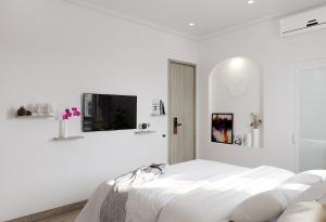 a white bedroom with a bed and a tv at Walhalla Hotel Saigon in Ho Chi Minh City